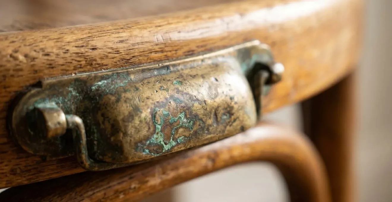 Détails de matériaux nobles vintage : laiton patiné et bois courbé créant des liens stylistiques entre époques