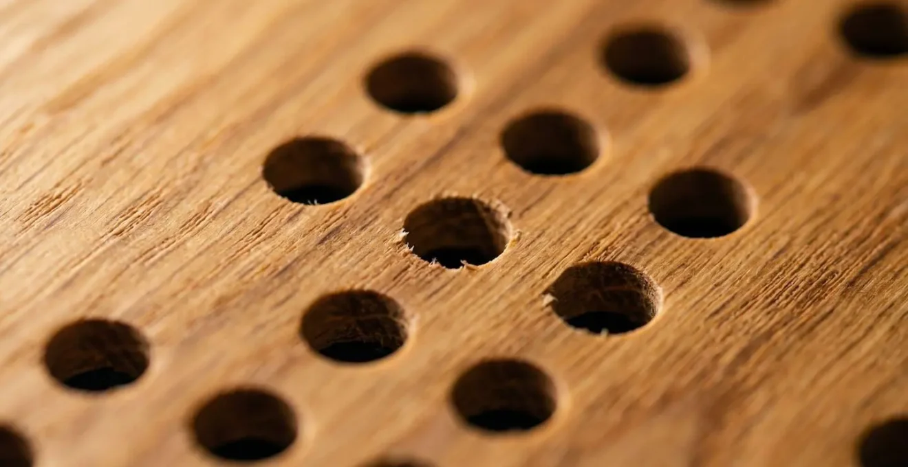 Gros plan sur la texture d'un panneau acoustique en bois perforé avec motif géométrique